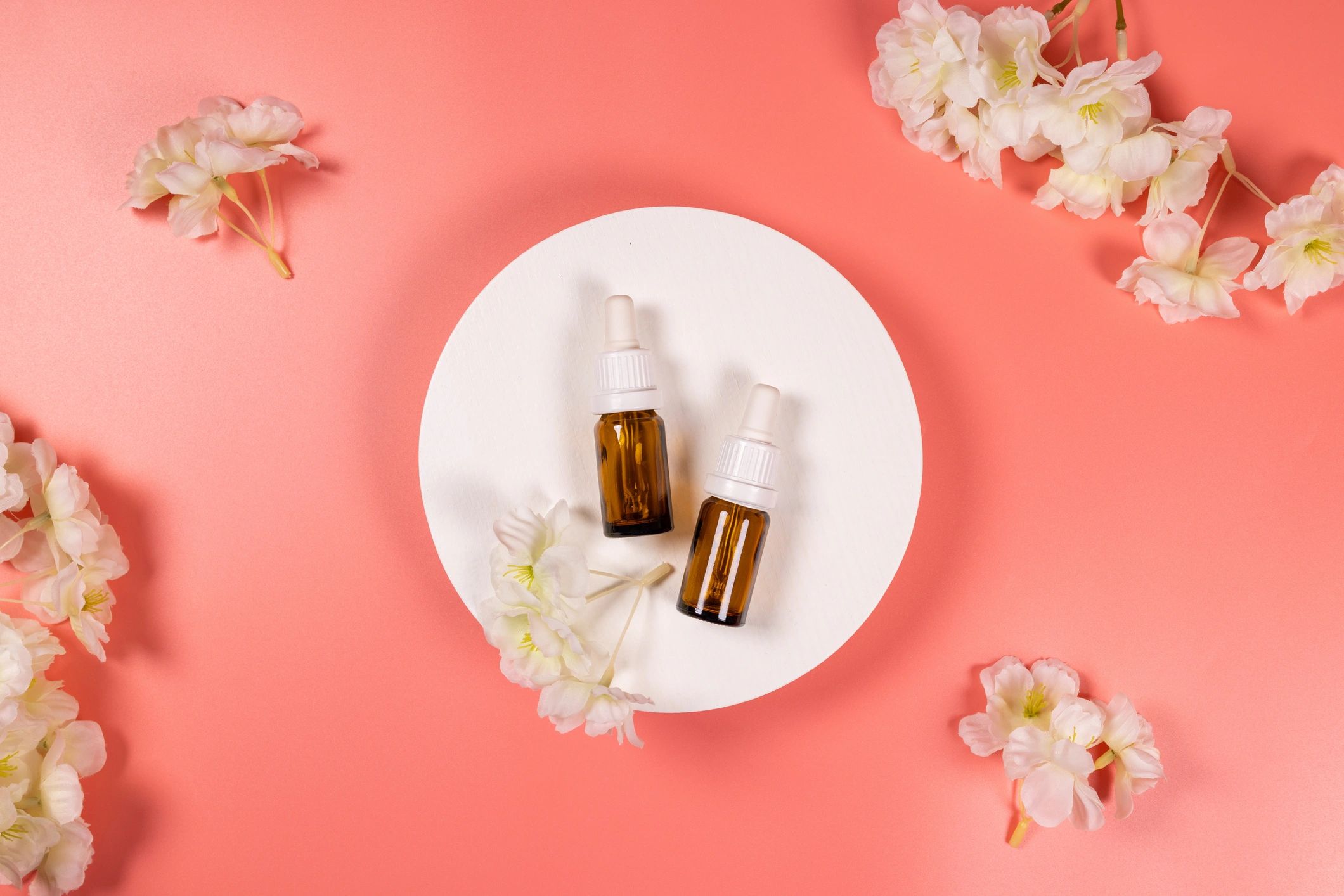 Skincare essential oil serum bottles on a pink background